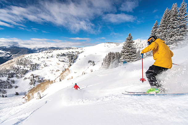 Two skiers skiing downhill on a trail